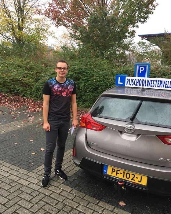 Jesse van Dijk uit Diever bij de lesauto na zijn examen