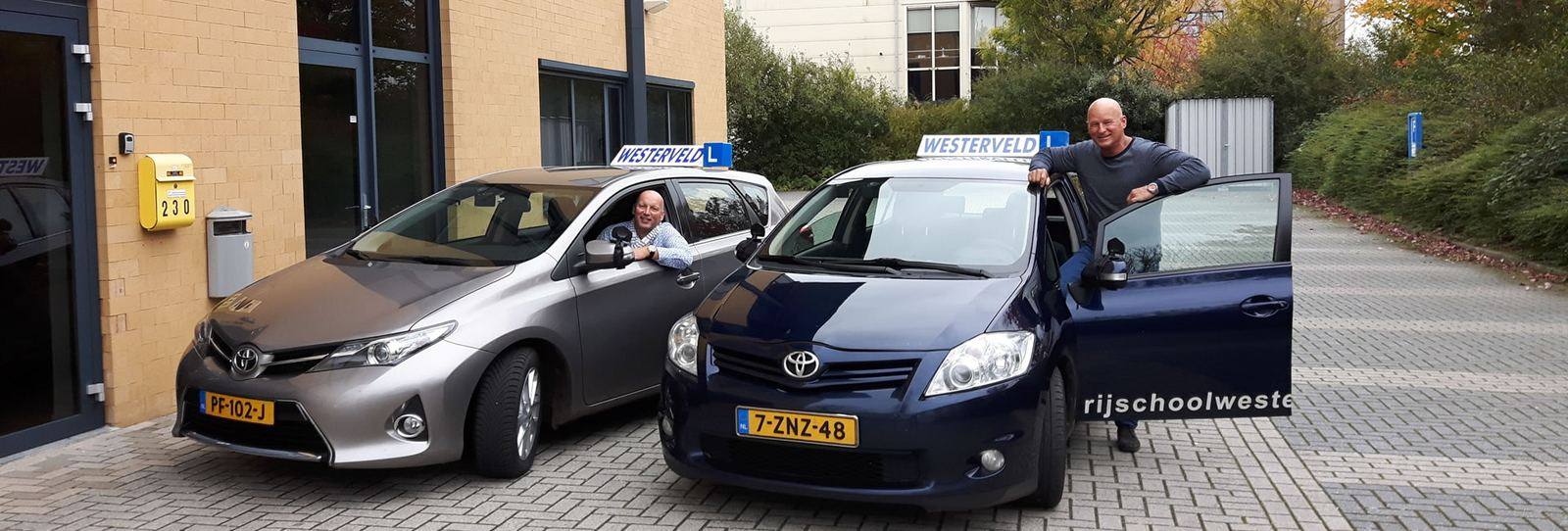 Twee instructeurs van Rijschool Westerveld bij hun lesauto's in Meppel
