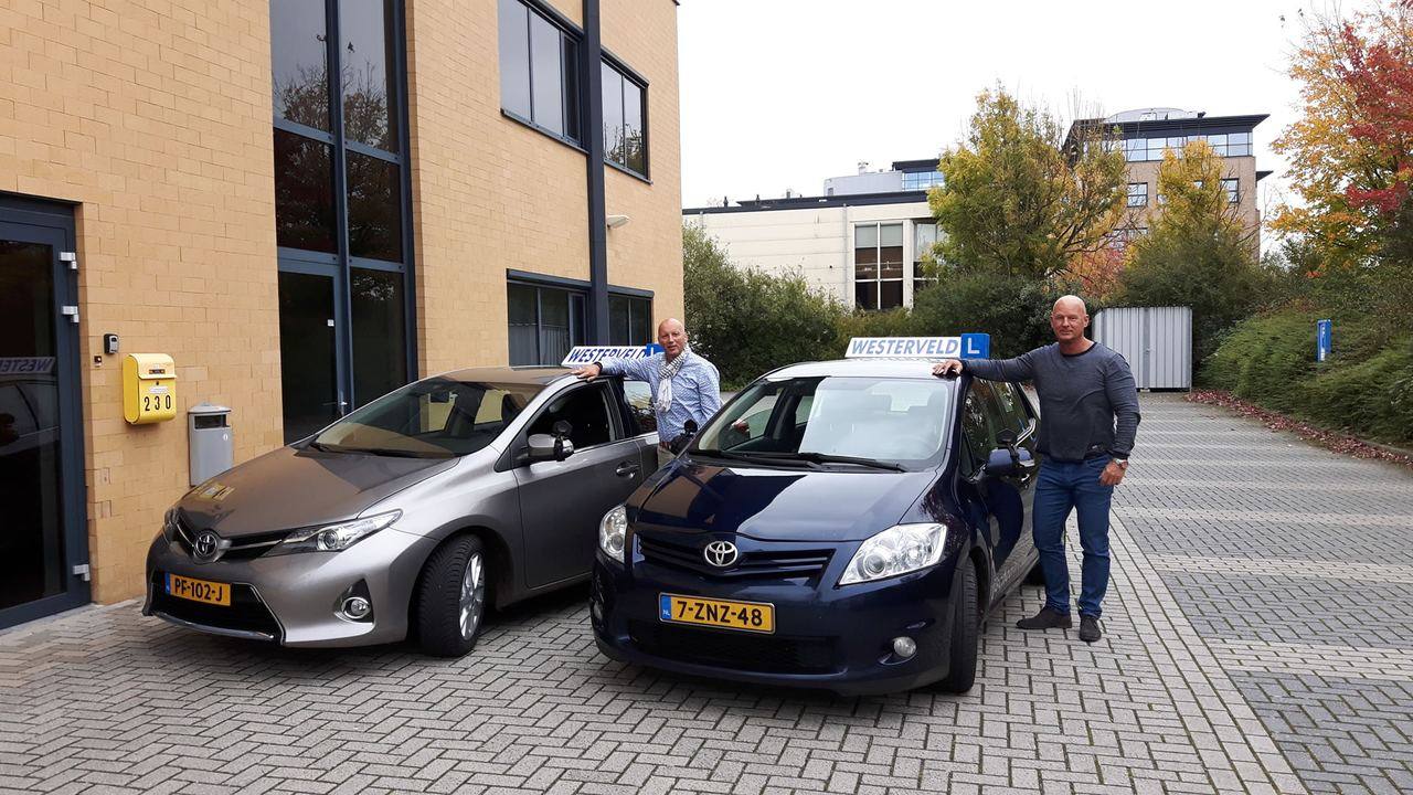 Twee instructeurs van Rijschool Westerveld bij de lesauto's aan de Weerddwarsstraat in Meppel